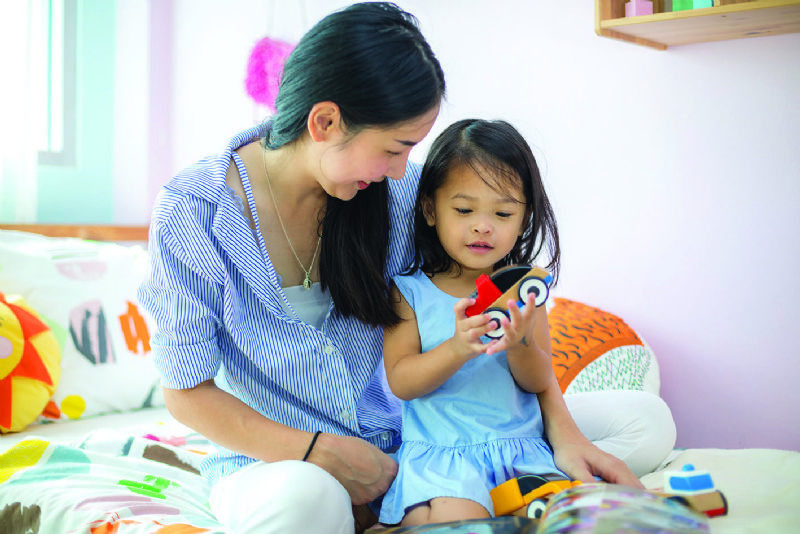 Mum and young daughter playing with toys in bedroom