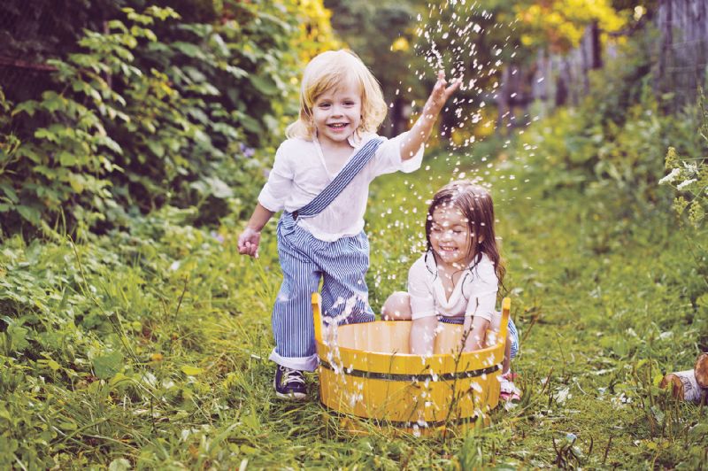 Two little girls playing with water in the garden hot summer heatwave