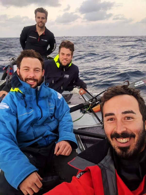 Four men on a boat. Jon Lakin is in the blue jacket