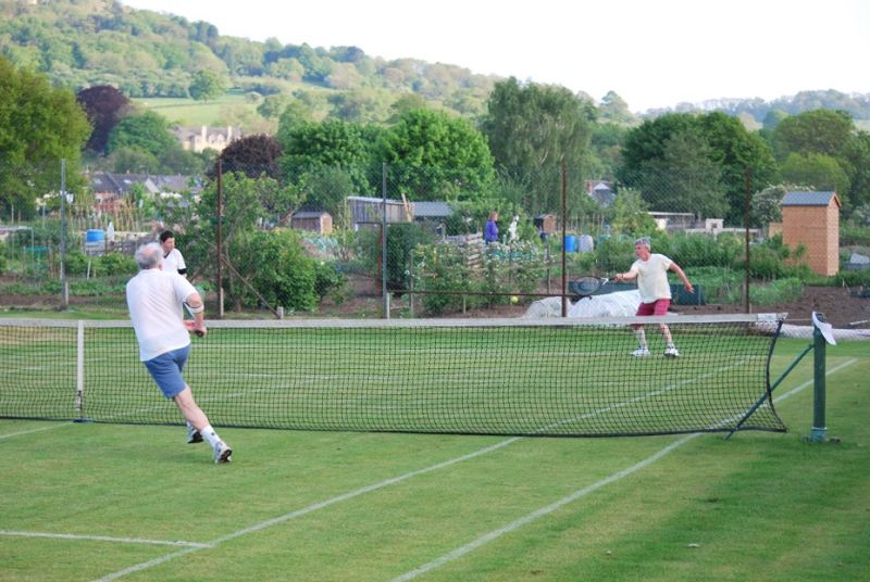 Dave Hughston, red shorts, in action at Leckhampton Lawn Tennis Club with the beautiful Leckhampton Hill in the background