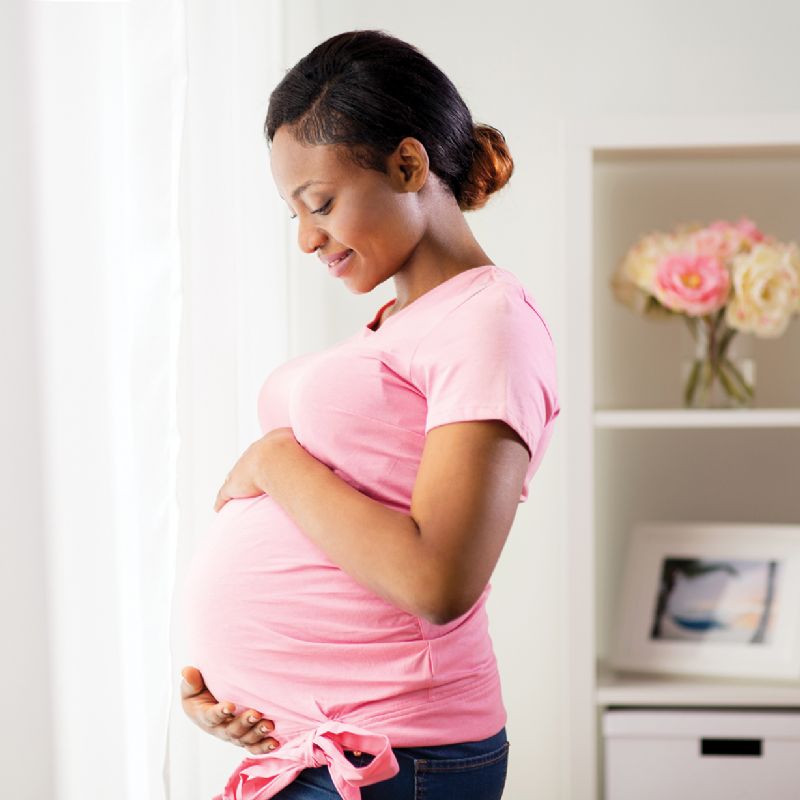 Pregnant woman smiling holding bump